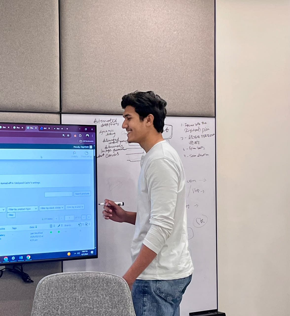 Hashir mapping a workflow beside a whiteboard and display